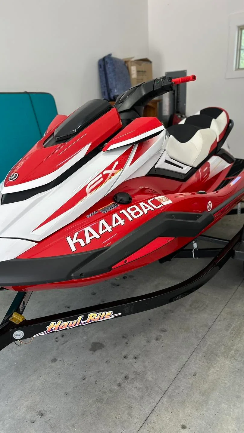 Red and white Yamaha EX jet ski on trailer, front three-quarter view