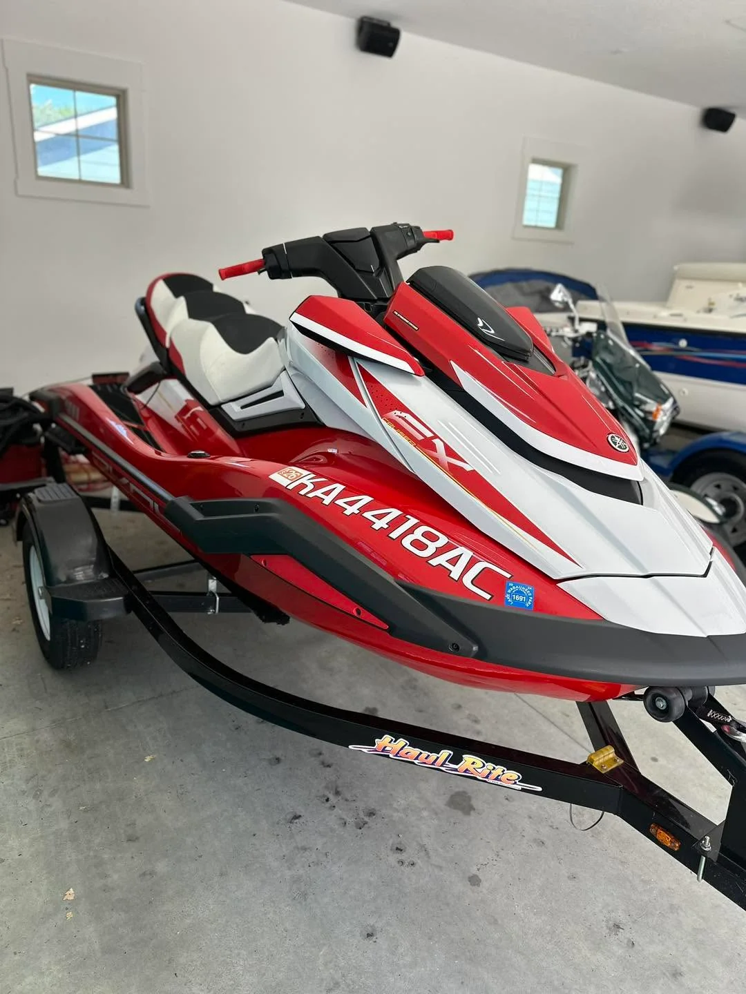Red and white Yamaha EX jet ski on trailer, side view