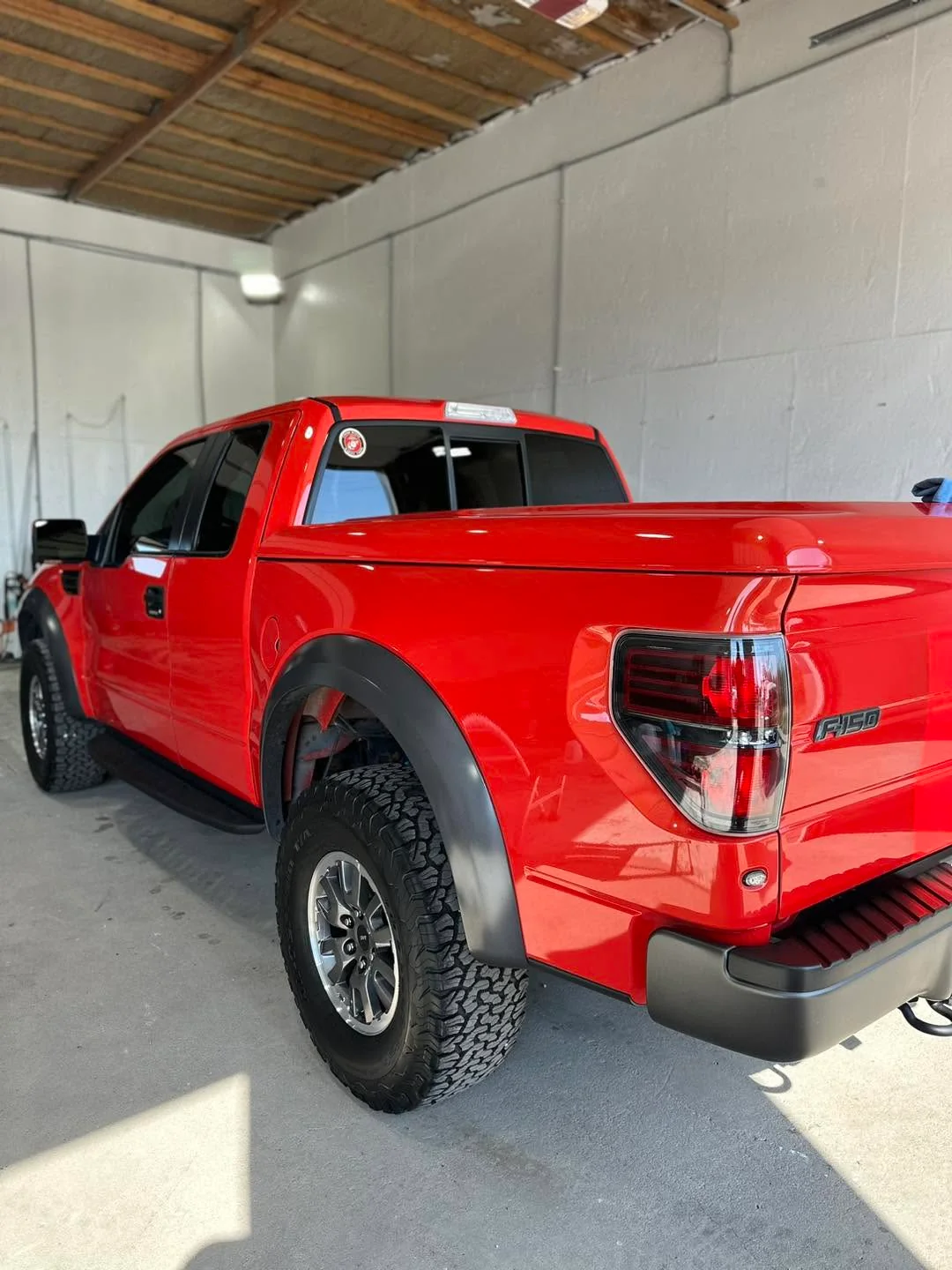 Red Ford Raptor F-150 pickup truck, rear three-quarter view