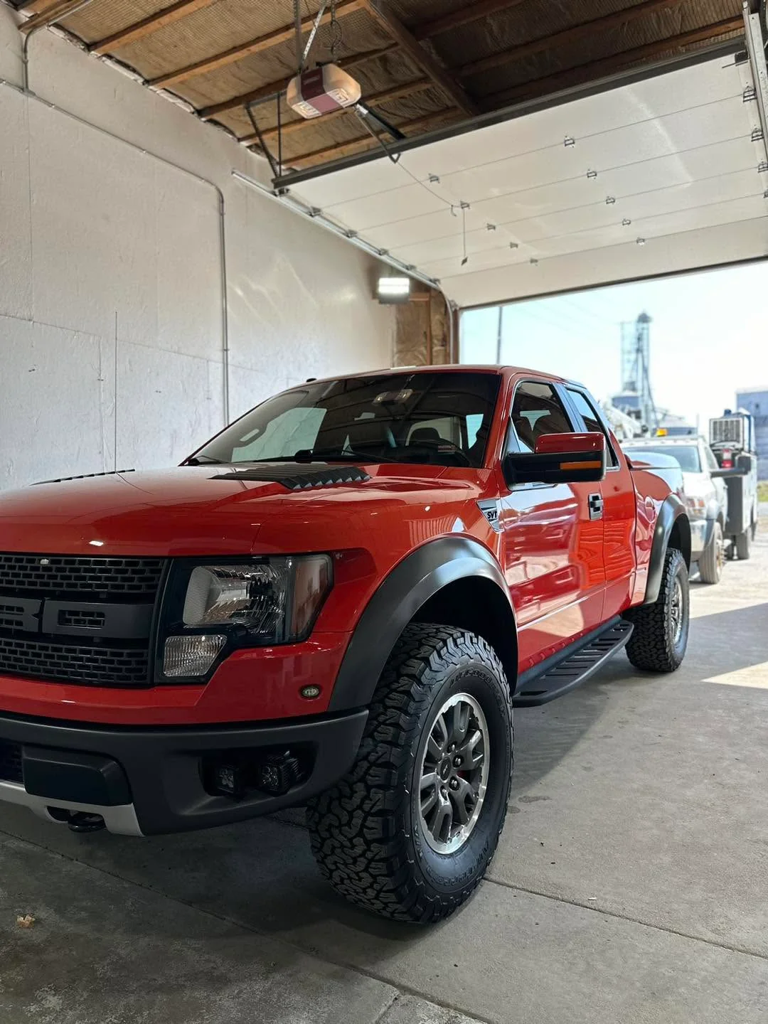 Orange-red Ford Raptor pickup truck, front three-quarter view
