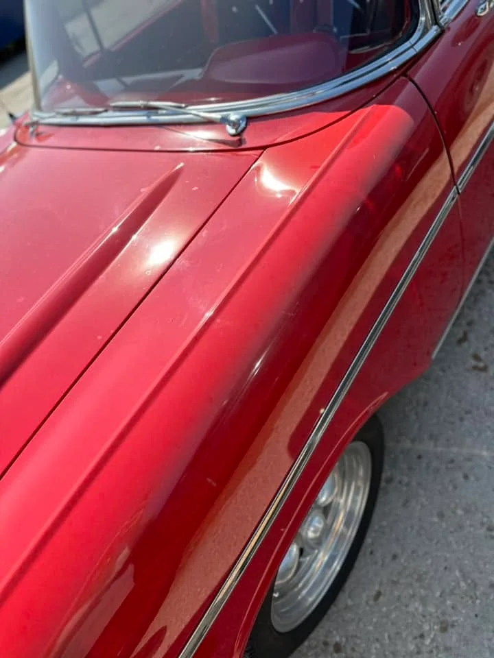 Dark red classic car hood and fender, close-up angled view