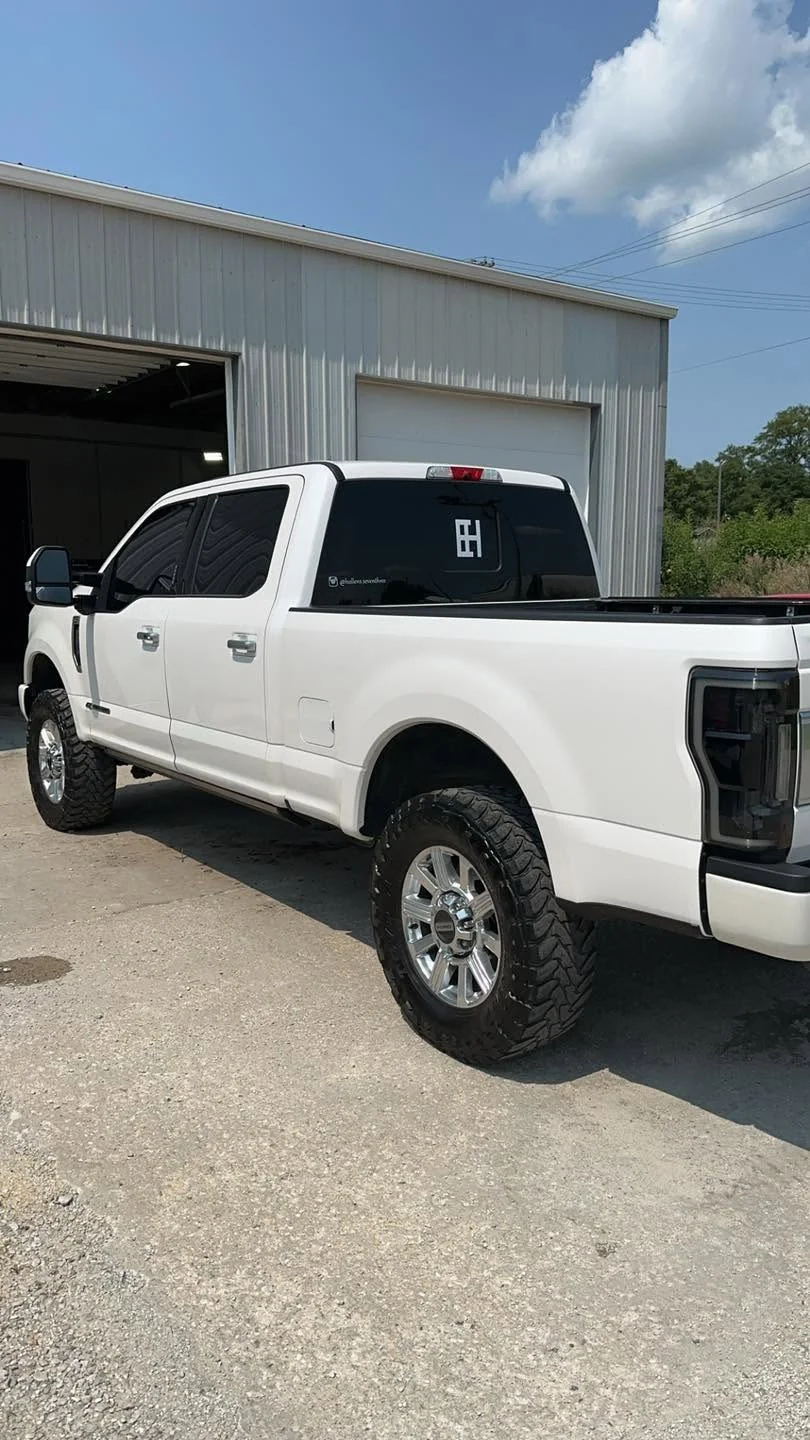 White Ford F-250 Super Duty lifted pickup, rear three-quarter view