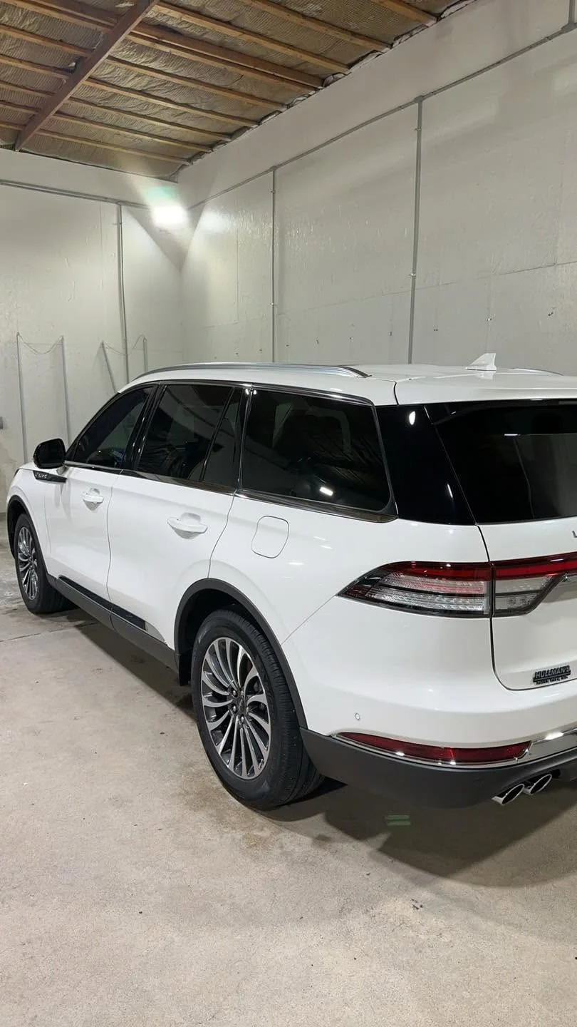 White Lincoln Aviator SUV, driver-side rear view in garage