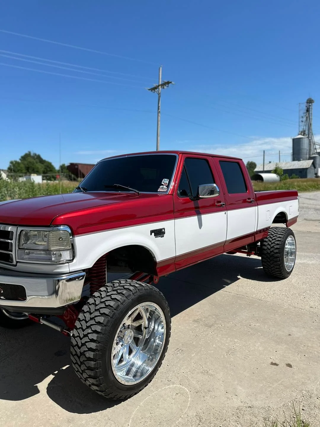 Red and white lifted Ford F-350 crew cab, front three-quarter view