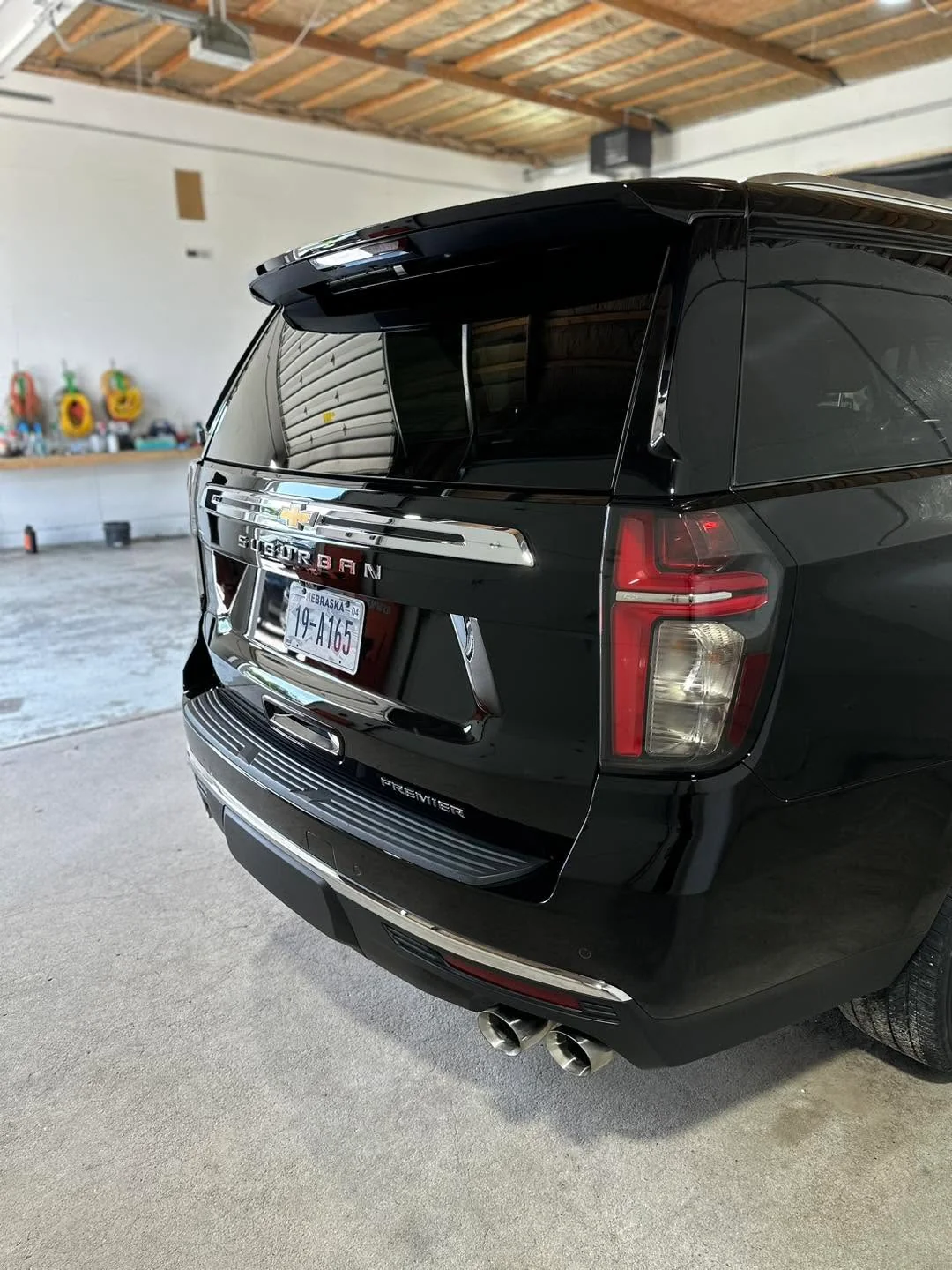 Black Chevrolet Suburban Premier SUV, rear three-quarter view in garage