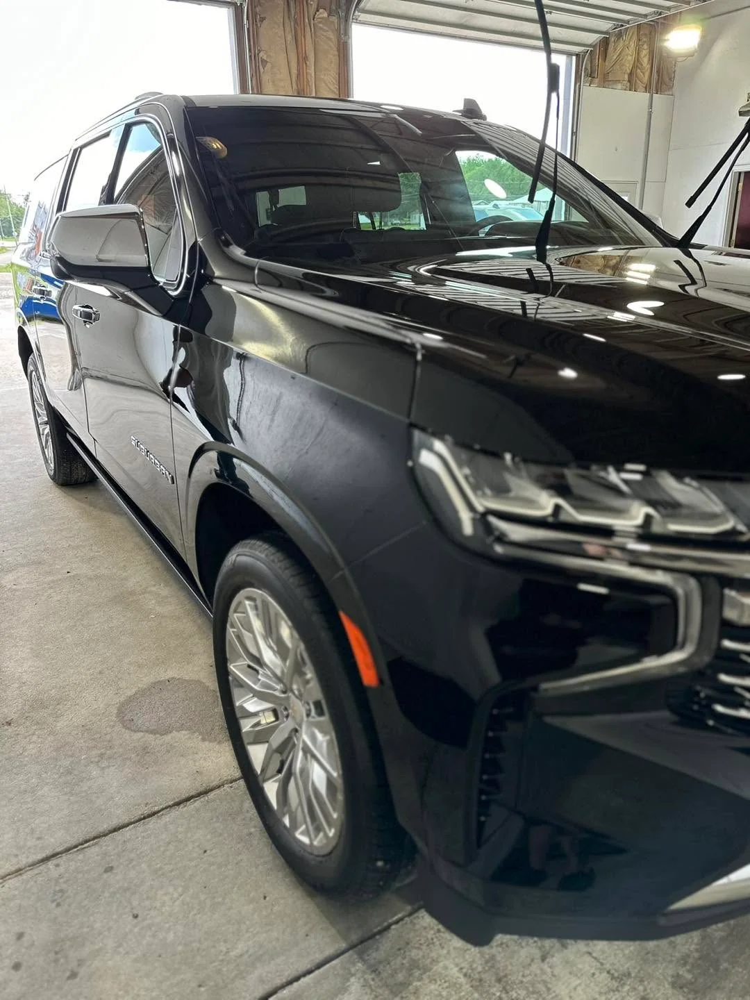 Black Chevrolet Suburban SUV, front three-quarter view in garage