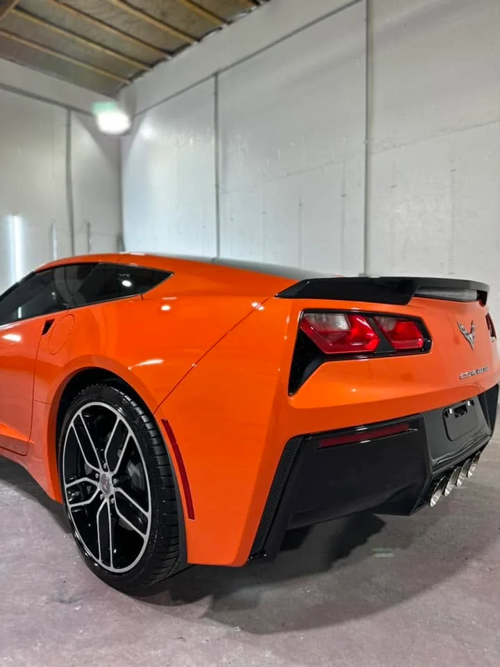 Orange Chevrolet Corvette C7 coupe, rear three-quarter view in garage