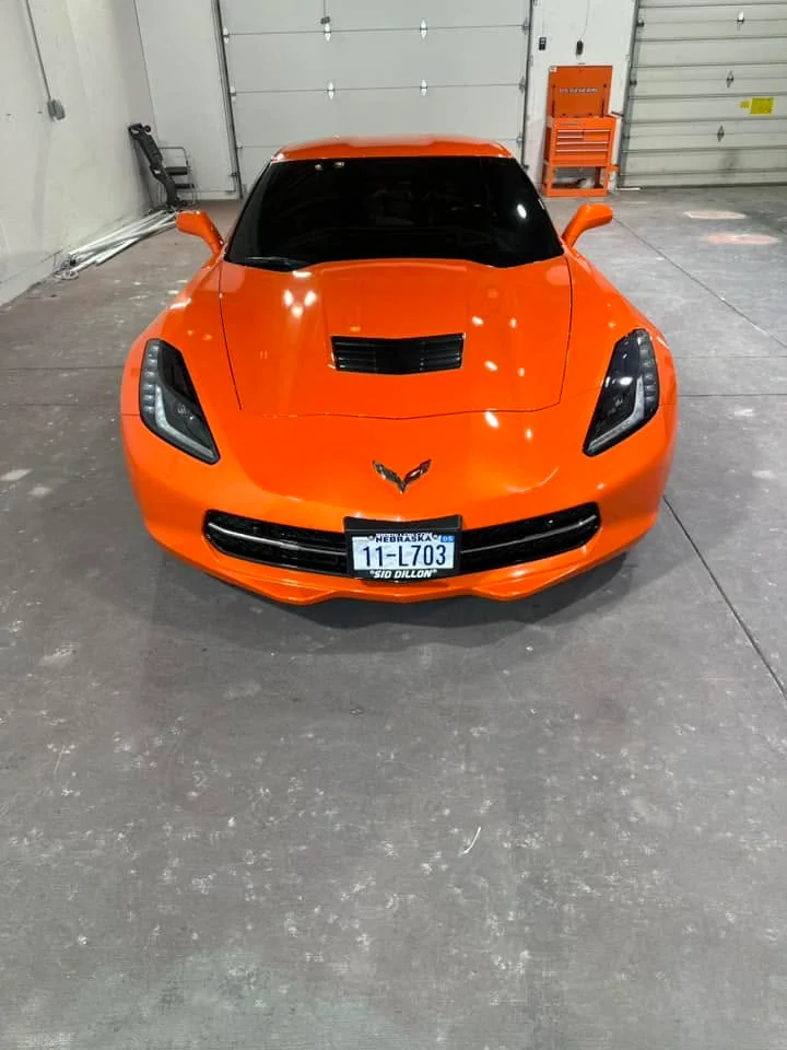 Orange Chevrolet Corvette Stingray, front view in shop