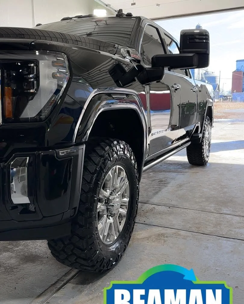 Black GMC Denali HD lifted pickup, low front three-quarter view