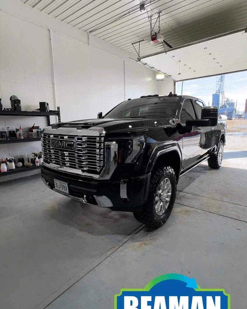 Black GMC Denali HD pickup, front three-quarter view in shop
