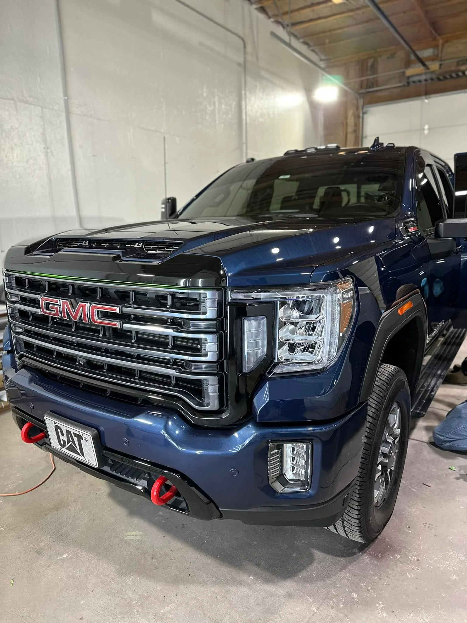Blue GMC Sierra AT4 pickup, front three-quarter view in shop